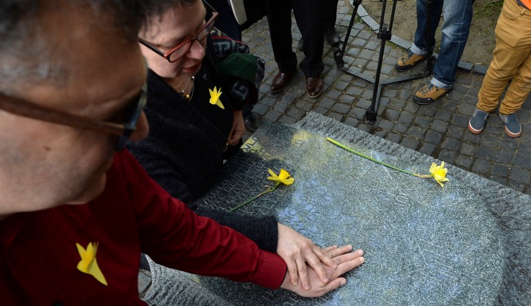 A man touches a monument when attending an independent ceremony in honor of the fighters of the 1943 Warsaw Ghetto Uprising on its 75th anniversary in Warsaw, Poland, Thursday, April 19, 2018.