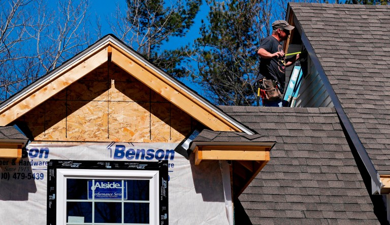 FILE- In this April 23, 2018, file photo, a worker installs vinyl siding on a new home in Auburn, N.H. On Tuesday, May 1, 2018, the Commerce Department reports on U.S. construction spending in March.