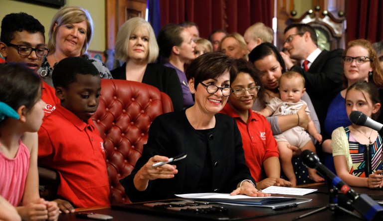 Iowa Gov. Kim Reynolds, center, signs a six-week abortion ban bill into law during a ceremony in her formal office on Friday in Des Moines, Iowa. The bill gives Iowa the strictest abortion restrictions in the nation, setting the state up for a lengthy court challenge.