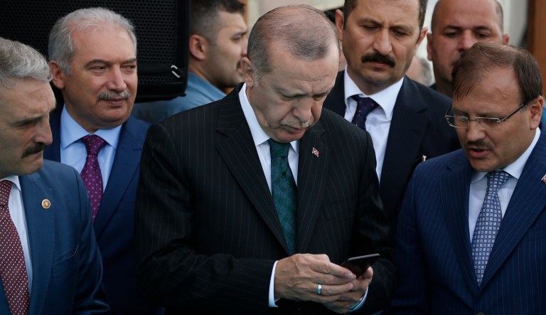 FILE-In this Friday, May 4, 2018 file photo, Turkey's President Recep Tayyip Erdogan, centre, looks at his phone during a ceremony for the re-opening of the Spice Bazaar following restoration in Istanbul. Thousands of people took to Twitter, Tuesday, May 8, 2018, to say "that's enough" to Erdogan who is running for re-election on June 24 presidential elections. 'Tamam' which roughly translate as "that's enough" became a worldwide trending topic on Twitter on Tuesday hours after Erdogan - who has been in power for the past 15 years _ said he would step aside 'if my people say 'that's enough'. 