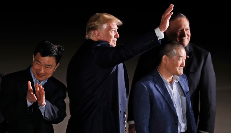 President Trump, accompanied by Secretary of State Mike Pompeo, back, waves at the media and others upon arrival of former North Korean detainees Tony Kim, left, Kim Dong Chul and Kim Hak Song, unseen, Thursday at Andrews Air Force Base, Md.