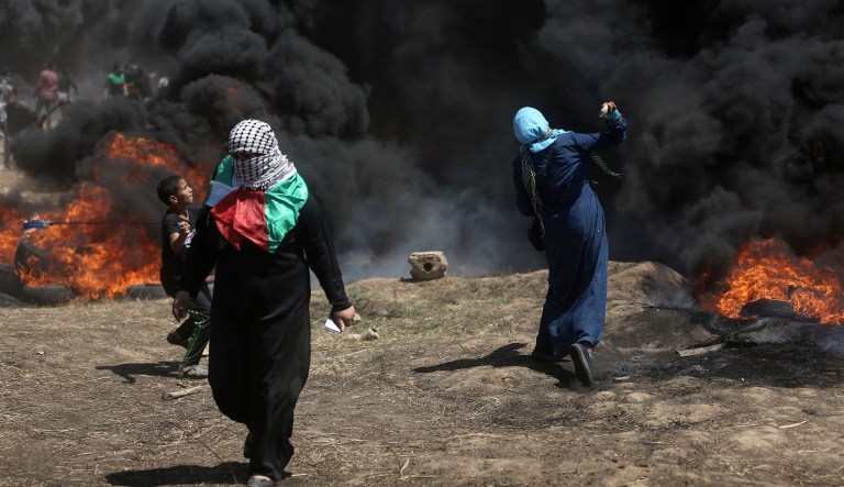 Palestinian protesters hurl stones at Israeli troops during a protest at the Gaza Strip's border with Israel, Monday, May 14, 2018. Thousands of Palestinians are protesting near Gaza's border with Israel, as Israel prepared for the festive inauguration of a new U.S. Embassy in contested Jerusalem. 