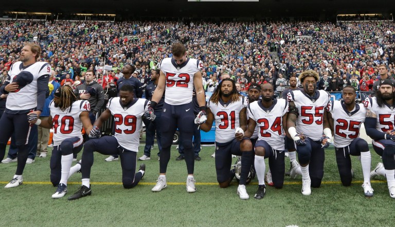 In this Oct. 29, 2017 file photo, Houston Texans players kneel and stand during the singing of the national anthem before an NFL football game against the Seattle Seahawks, in Seattle.