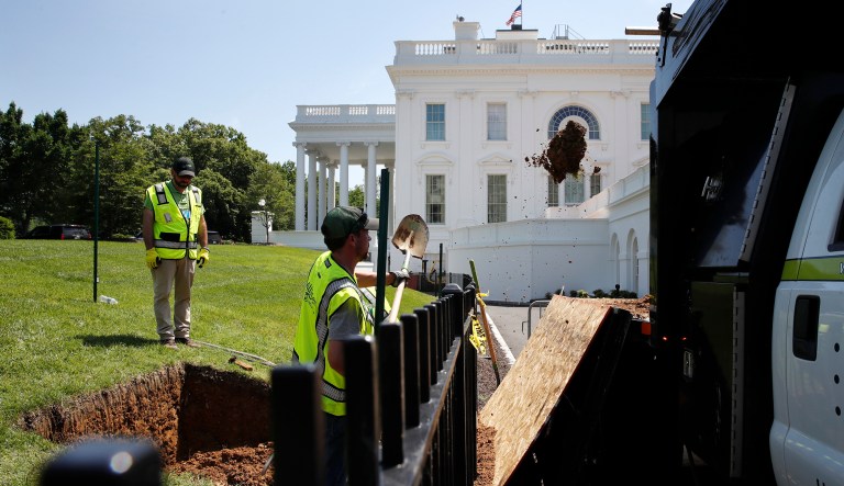 Workers shovel dirt from a sinkhole as it is repaired on the North Lawn of the White House in Washington.