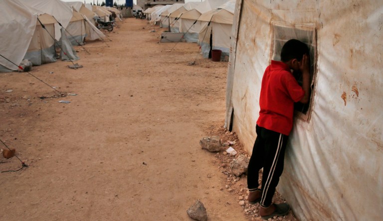 A child looks inside a tent at a refugee camp for people fleeing the Islamic State.