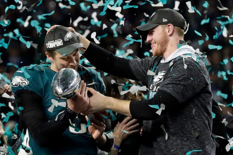 FILE - In this Feb. 4, 2018 photo, Philadelphia Eagles quarterback Carson Wentz, right, hands the Vincent Lombardi trophy to Nick Foles after winning the NFL Super Bowl 52 football game against the New England Patriots in Minneapolis. The Eagles won 41-33.  President Donald Trump has called off a visit by the Philadelphia Eagles to the White House Tuesday due to the dispute over whether NFL players must stand during the playing of the national anthem. Trump says in a statement that some members of the Super Bowl championship team âdisagree with their President because he insists that they proudly stand for the National Anthem, hand on heart.â Trump says the team wanted to send a smaller delegation, but fans who planned to attend âdeserve better.â  