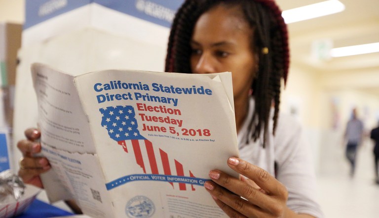 Nikko Johnson reviews the California Primary election guide at San Francisco City Hall Tuesday, June 5, 2018. The 40-year-old nurse was waiting for her mother to arrive at the polling station so they could vote together.