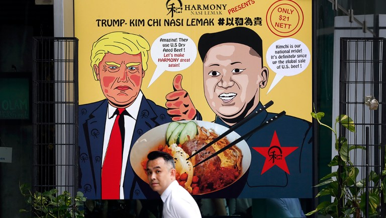 A man walks past an advertisement board of cartoon caricatures of President Trump and North Korean leader Kim Jong Un. (AP Photo/Wong Maye-E)