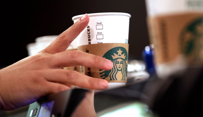 In this May 29, 2018, file photo, a barista reaches for an empty cup at a Starbucks, commonly referred to as the original Starbucks, in the Pike Place Market in Seattle.