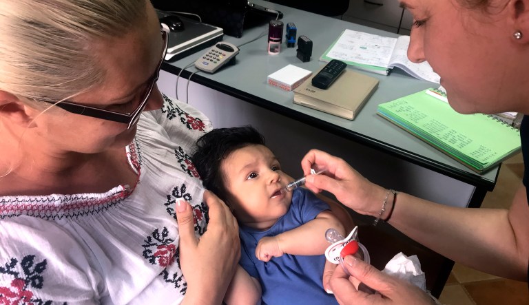 In this photo taken on Wednesday, June 6, 2018 picture, a child gets a dose of vaccine in Chitila, Romania. An outbreak of measles has killed dozens of infants and children in Romania, with 200 new cases reported each week. Doctors say the surge in the disease is aided by low rates of vaccination, fueled in part by media campaigns waged by celebrities who warn of the perils of immunization and also by rural superstitions.