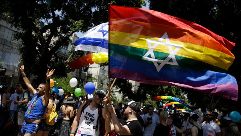 Israelis and tourists wave flags as they participate in the Gay Pride parade.
