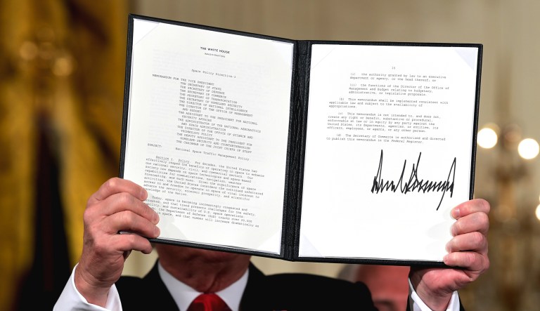 President Trump shows off a "Space Policy Directive" after signing it during a meeting of the National Space Council in the East Room of the White House on June 18 in Washington.