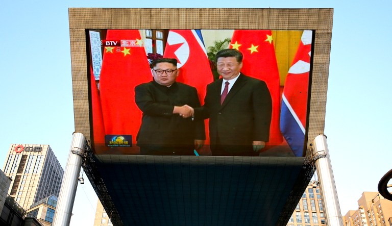 A giant TV screen broadcasts the meeting of North Korean leader Kim Jong Un (left) and Chinese President Xi Jinping during a welcome ceremony at the Great Hall of the People in Beijing on Tuesday.
