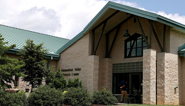 A person walks into the entrance of the Shenandoah Valley Juvenile Center on Wednesday in Staunton, Va. Immigrant children as young as 14 housed at the juvenile detention center say they were beaten while handcuffed and locked up for long periods in solitary confinement, left nude and shivering in concrete cells.