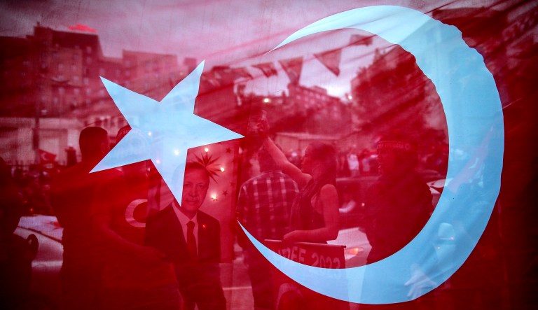 In this photo taken late Sunday, seen behind a Turkish flag, supporters of Turkey's President and ruling Justice and Development Party, or AKP, leader Recep Tayyip Erdogan, gather during celebrations outside the party headquarters in Istanbul. Erdogan, 64 who has dominated Turkish politics for the past 15 years, is the winner of Sunday's polls and was set to extend his rule with sweeping new powers after winning landmark presidential and parliamentary elections.