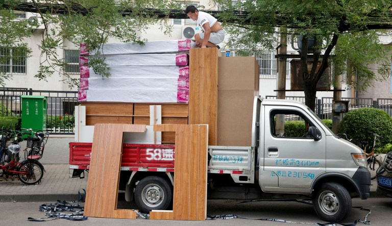A worker climbs onto of a delivery truck loaded with mattresses in Beijing, China.