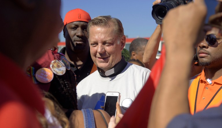 The Rev. Michael Pfleger (pictured center) speaks to protesters before marching on the Dan Ryan Expressway on Saturday in Chicago. The protesters shut down the expressway to draw attention to the city's gun violence and pressure public officials to do more to help neighborhoods hardest hit by it.