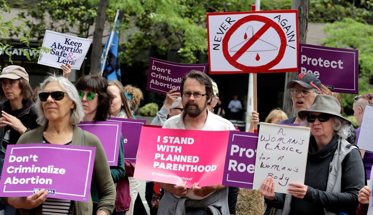 Protesters hold signs as they listen to a speaker during a protest in Seattle against President Trump and his choice of federal appeals Judge Brett Kavanaugh as his second nominee to the Supreme Court.