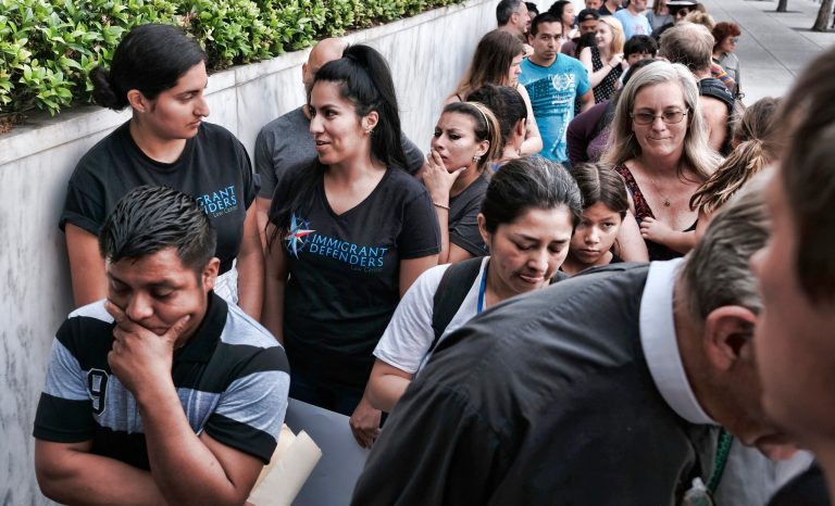 Hermelindo Che Coc, left, from Guatemala waits in line prior to a required check-in with immigration enforcement authorities in downtown Los Angeles on Tuesday, July 10, 2018. 