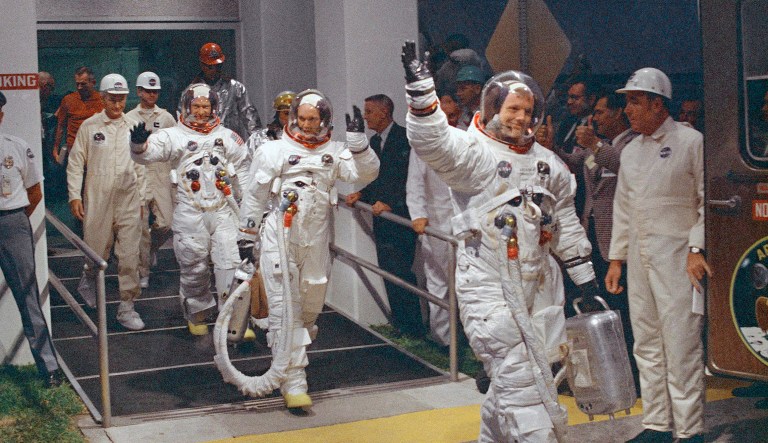 Neil Armstrong waving in front, heads for the van that will take the crew to the rocket for launch to the moon at Kennedy Space Center in Merritt Island, Fla.