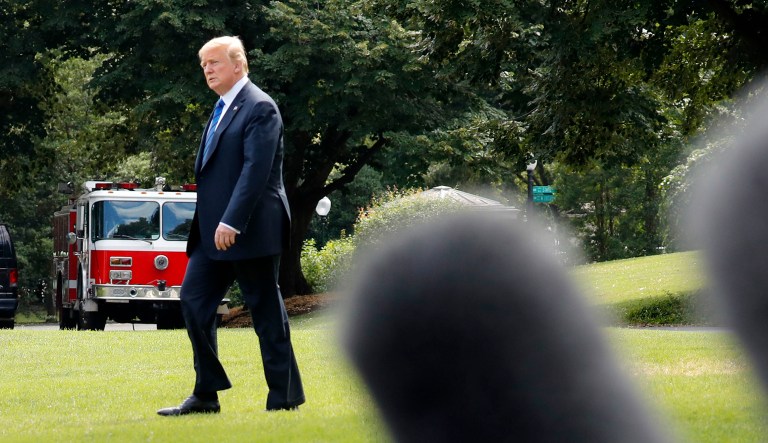 Television microphones are extended out as President Trump walks across the South Lawn of the White House in D.C.