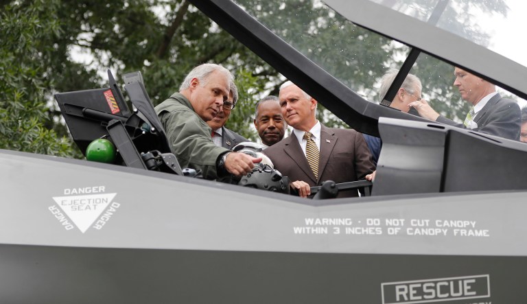 Vice President Mike Pence, right, listens to Alan Norman, left, the Lockheed Martin F-35 Test Pilot, as he looks at the cockpit of a F-35 fighter jet, while touring the "Made in America" product showcase, featuring items created in each of the U.S. 50 states, at the White House in Washington, Monday, July 23, 2018. With Pence are Energy Secretary Rick Perry, second from the left, and Housing and Urban Development Secretary Ben Carson, second from the right. 