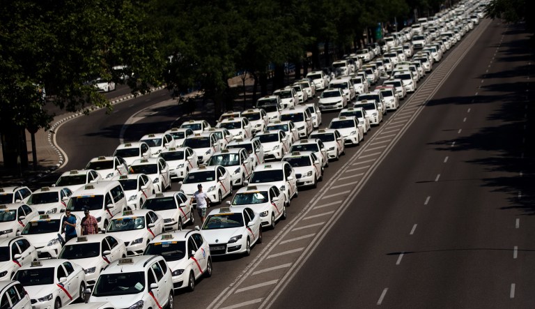 Parked taxis block the main Castellana avenue in Madrid on July 30, 2018, protesting the proliferation of private ride-hailing services.