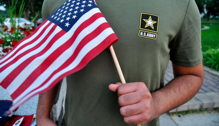 In this July 3, 2018, file photo, a Pakistani recruit, 22, who was recently discharged from the U.S. Army, holds an American flag as he poses for a picture.