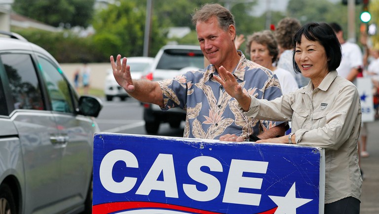 Ed Case, left, along with his wife Audrey Case, do last minute campaigning waving at passing cars.