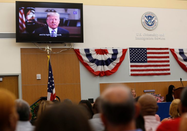 New American citizens watch a recorded message from President Trump during a naturalization ceremony at the U.S. Citizenship and Immigration Services Miami Field Office, Friday, Aug. 17, 2018, in Miami.
