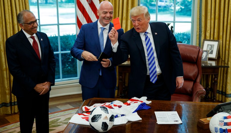 President Donald Trump holds up a red card during a meeting with FIFA president Gianni Infantino, center, and United States Soccer Federation president Carlos Cordeiro, left, in the Oval Office of the White House, Tuesday, Aug. 28, 2018, in Washington.