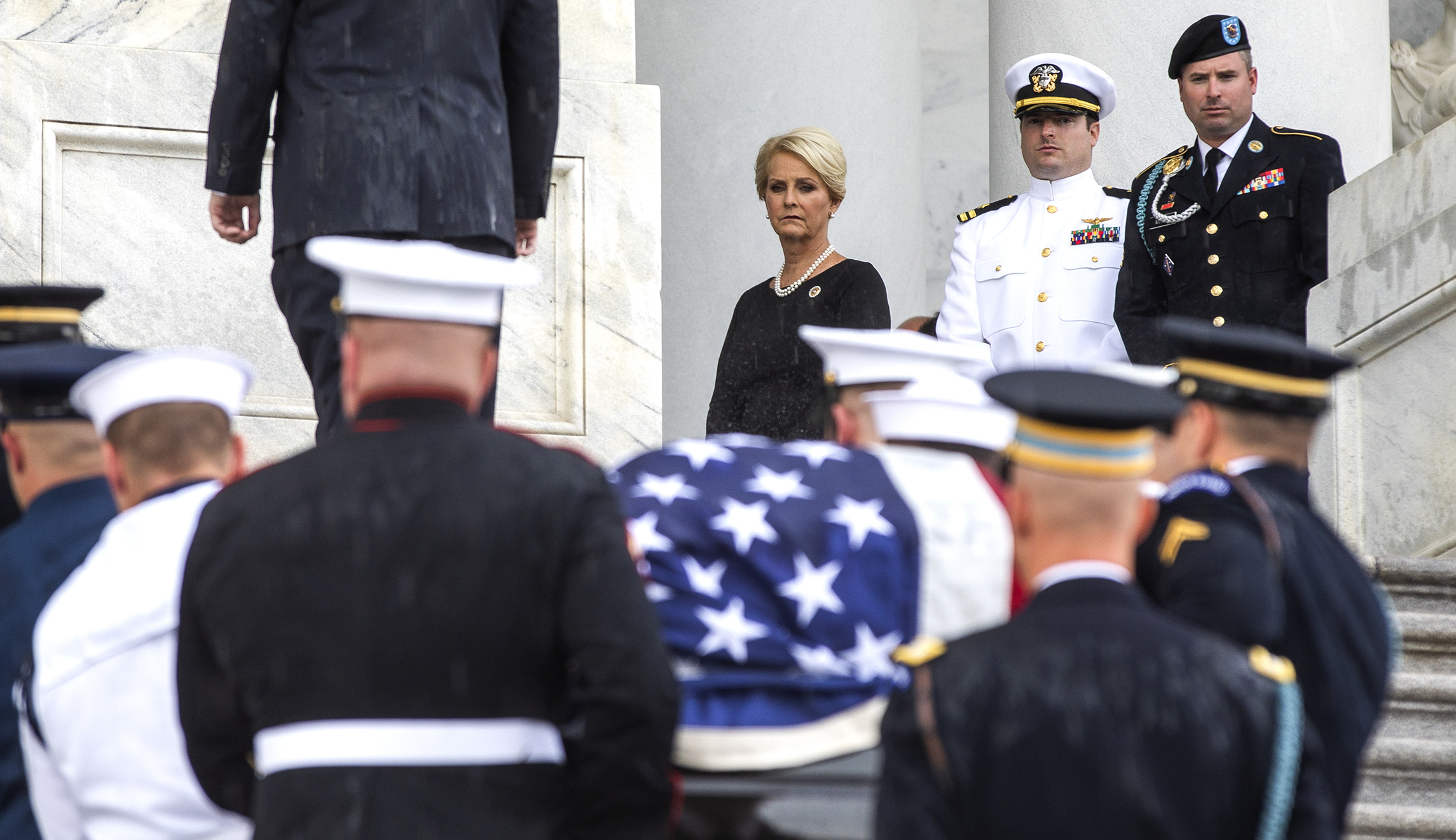 The flag-draped casket of Sen. John McCain, R-Ariz., is carried up the steps of the U.S. Capitol, Friday, Aug. 31, 2018, in Washington as Cindy McCain, top right, joined by her sons Jack McCain, and James McCain, look on.