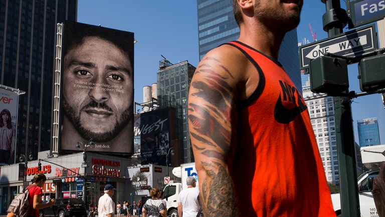 People walk by a Nike advertisement featuring Colin Kaepernick on display.