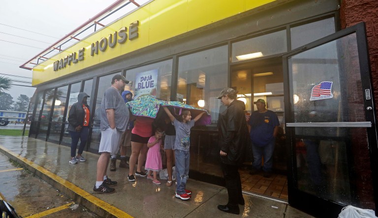 Luke Churchill, left, stands with his wife, Mary and their children, Katie, 13, Liam, 9, and Raighan, 3, as they wait in the rain outside an open Waffle House restaurant in Wilmington, N.C., after Hurricane Florence traveled through the area Sunday, Sept. 16, 2018.