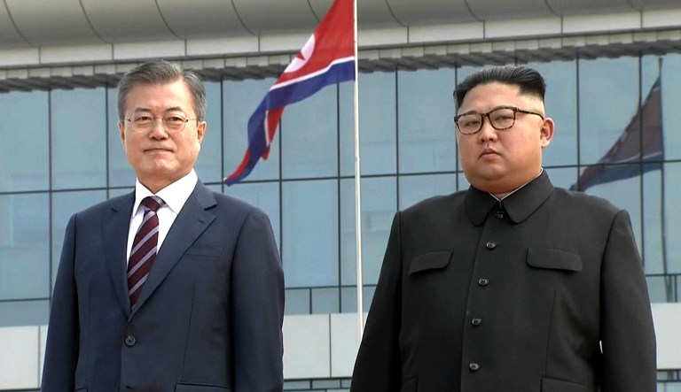 In this image made from video provided by Korea Broadcasting System, South Korean President Moon Jae-in (left) poses with North Korean leader Kim Jong Un for a photo on the podium upon arrival in Pyongyang, North Korea.