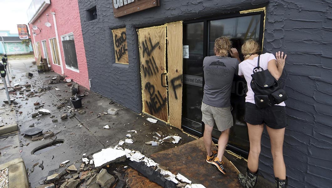 Crush & Grind owners Brett Gurkin, left, and Nadine Antonelli look into their business along the Carolina Beach Boardwalk in Carolina Beach, N.C.