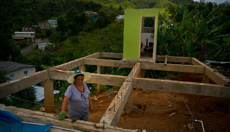 In this Sept. 8, 2018 photo, Alma Morales Rosario poses for a portrait between the beams of her home being rebuilt after it was destroyed by Hurricane Maria one year ago in the San Lorenzo neighborhood of Morovis, Puerto Rico.