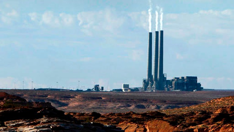 Smoke rises from the stacks of the main plant facility at the Navajo Generating Station, as seen from Lake Powell in Page, Ariz.