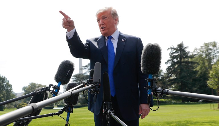 President Trump gestures while answering questions from members of the media before walking across the South Lawn of the White House in Washington, Tuesday, Oct. 2, 2018.