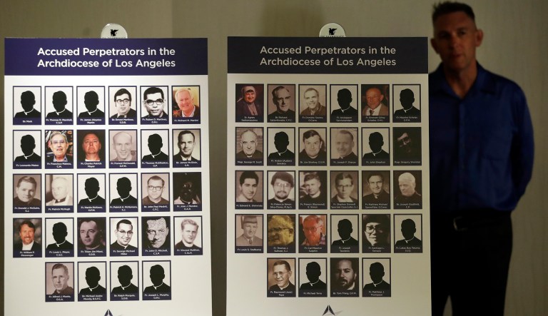 Tom Emens, right, who was sexually abused by a priest, stands behind a list of accused clergy Tuesday, Oct. 2, 2018, in Los Angeles. Survivors of clergy sex assault announced the filing of a nuisance lawsuit against California Roman Catholic bishops for covering up abuse.
