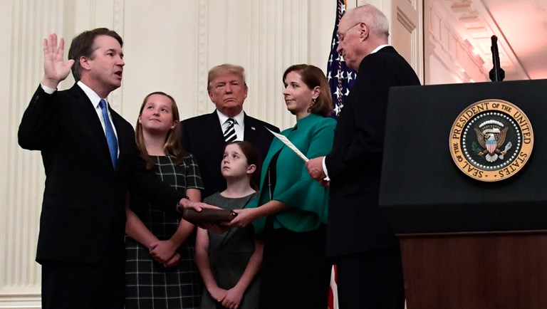 Retired Justice Anthony Kennedy, right, ceremonially swears-in Supreme Court Justice Brett Kavanaugh, as President Donald Trump looks on, in the East Room of the White House.