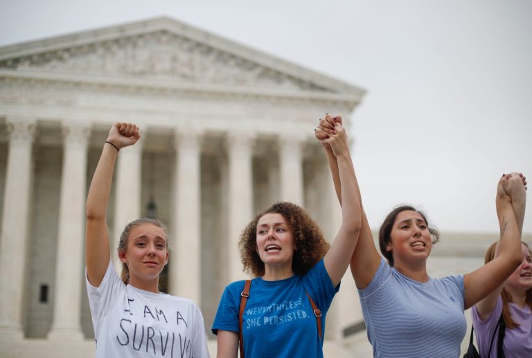 From left to right, Elizabeth Gillette, 19, Ashley Stewart, 19, and Emma Salas, 18, all student from George Mason University, join other activists as they protest in front of the Supreme Court in Washington, Tuesday, Oct. 9, 2018. 