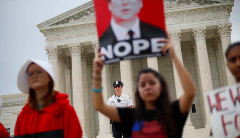 A police officer guards the front steps of the Supreme Court in Washington as activists protest, Tuesday, Oct. 9, 2018. A Supreme Court with a new conservative majority takes the bench as Brett Kavanaugh, narrowly confirmed after a bitter Senate battle, joins his new colleagues to hear his first arguments as a justice.