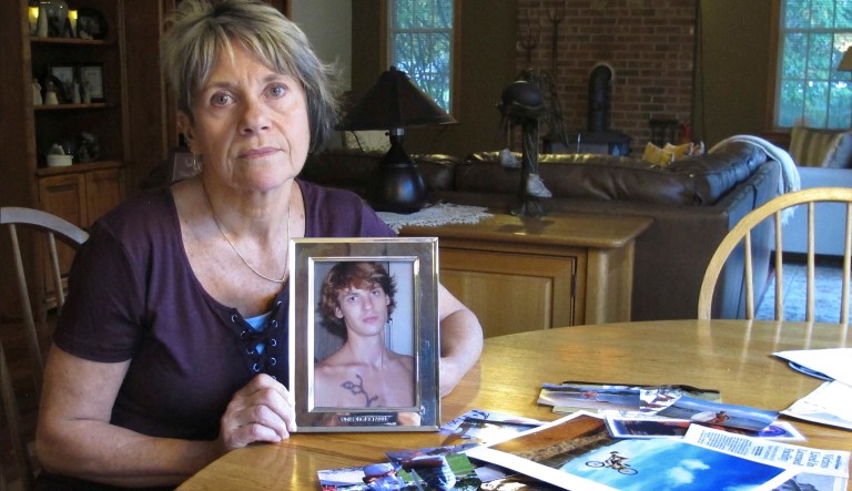 In this Oct. 9, 2018 photo, Linda Marino poses with photographs of her son, Samuel, at her home in Tolland, Conn. Samuel Marino died in a 2009 car crash that relatives believe was intentional after becoming a victim of a male sex trafficking ring. Advocates are calling for more recognition and services for male victims. 