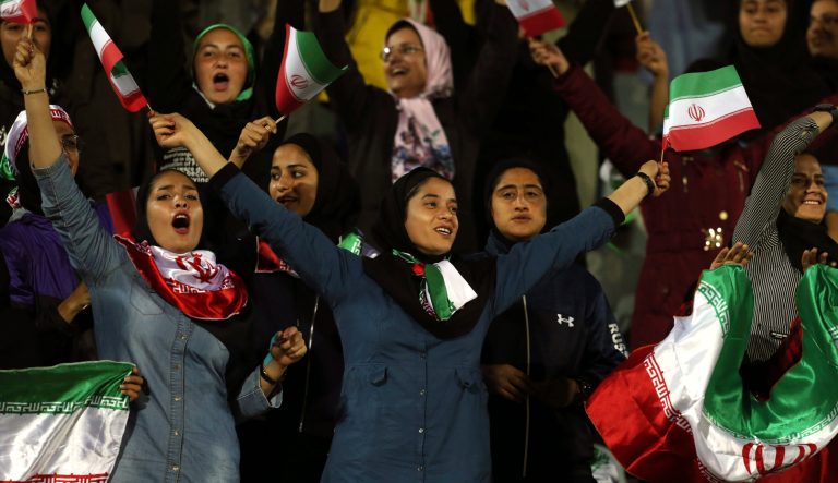Female Iranian spectators cheer as they wave their country's flag during a friendly soccer match between Iran and Bolivia, at the Azadi (Freedom) stadium, in Tehran, Iran, Tuesday, Oct. 16, 2018. In a rare move, authorities allowed a select group of women into Azadi stadium to watch a men's soccer match. 