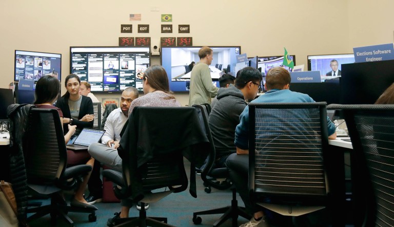 Workers gather and sit and their desks during a demonstration in the war room, where Facebook monitors election related content on the platform, in Menlo Park, Calif.