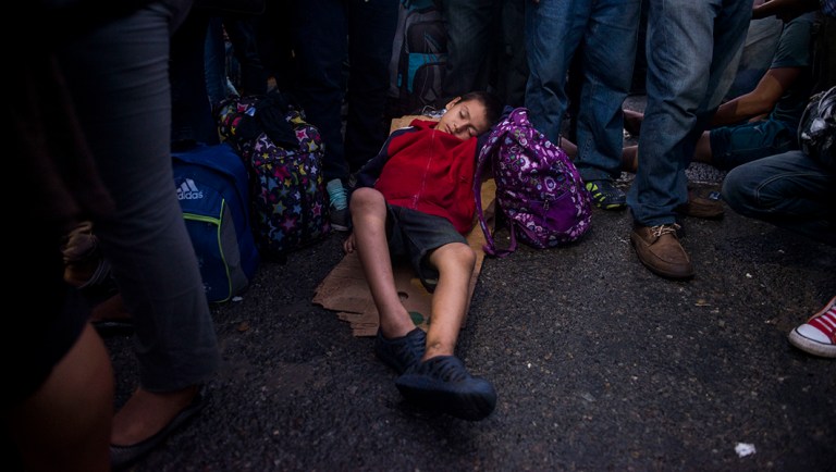 A migrant child sleeps on a piece of cardboard as the group he is traveling with waits to be attended by Mexican immigration authorities on a bridge that stretches over the Suchiate River, connecting Guatemala and Mexico.