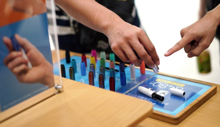 Visitors look at a pen-like "heat-not-burn" device iQOS at an IQOS store in Tokyo.