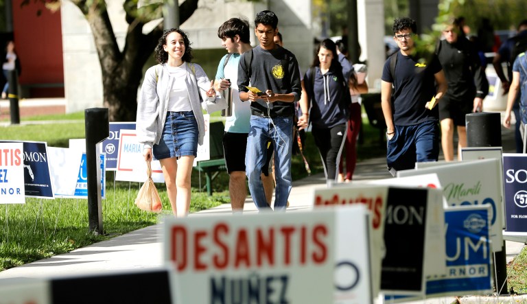 Students walk past campaign signs next to an early voting site on the Miami Dade College campus in Miami. Early voting is available for the first time on the campuses of Florida's major state colleges and universities. 
