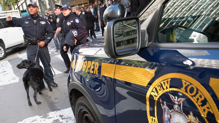 Emergency service personnel with a bomb-sniffing dog work outside the building that houses New York Gov. Andrew Cuomo's office after a report of a suspicious package.